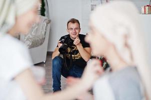 hombre fotógrafo disparando en el estudio a dos chicas mientras hacen su propia crema de máscaras. fotógrafo profesional en el trabajo. foto