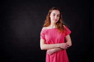 Young girl in red dress against black background on studio. photo