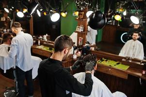 apuesto hombre barbudo en la barbería, peluquero en el trabajo. foto