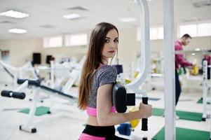 Young brunette sexy slim girl doing workout at gym. photo