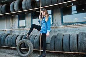 Young hipster girl in jeans jacket and head scarf at tire fitting zone. photo