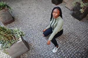 City portrait of positive young dark skinned female wearing green hoody. photo