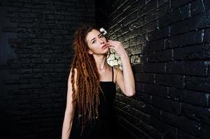 Studio shoot of girl in black with dreads on brick background. photo