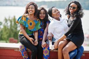 grupo de cuatro chicas afroamericanas sentadas al aire libre y divirtiéndose. foto