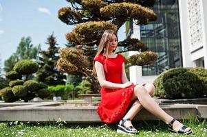 Teenage girl in red dress posed outdoor at sunny day. photo