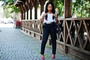 elegante mujer de negocios afroamericana con bolso en las calles de la ciudad. foto