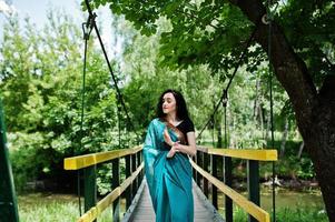 retrato de una hermosa niña brumette india o modelo de mujer hindú en el puente. traje tradicional indio lehenga choli. foto