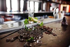 Alcoholic spilled coctail with mint and ice at bar table. photo