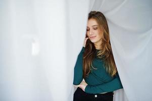 Handsome brunette girl wear on green, posing at curtains. Studio model portrait. photo