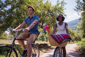 joven pareja multiétnica dando un paseo en bicicleta en la naturaleza foto