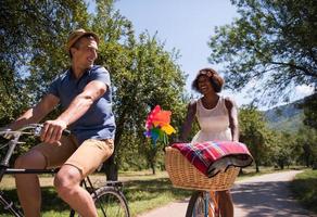 joven pareja multiétnica dando un paseo en bicicleta en la naturaleza foto