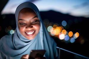 joven musulmana en la calle por la noche usando el teléfono foto