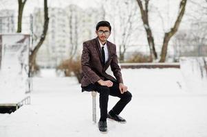 Elegante estudiante indio con traje y gafas posó en el día de invierno al aire libre. foto