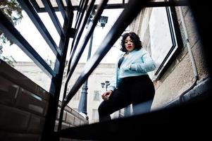 Stylish african american plus size model at streets of city on winter day. photo