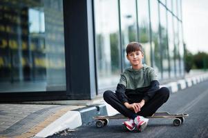 muchacho adolescente en un traje deportivo con longboard. foto