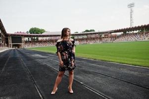 Portrait of a fabulous girl in dress and high heels on the track at the stadium. photo