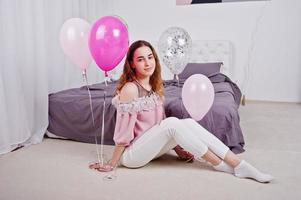 Young girl with balloons on bed posed on studio room. photo
