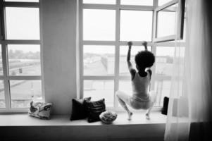 joven afroamericana en camiseta rosa contra la ventana. mañana perfecta. foto