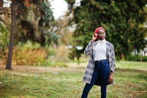 Young modern fashionable, attractive, tall and slim african muslim woman in hijab or turban head scarf and coat posed at park. photo