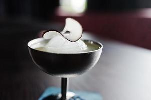 Alcoholic cocktail with ice and coconut in silver glass on bar table. photo