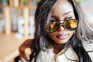 Close up face of african american girl in sunglasses posed at modern cafe . photo