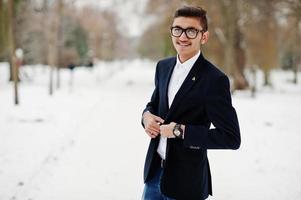 Elegante estudiante indio con traje y gafas posó en el día de invierno al aire libre. foto