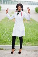 Young african american female doctor in white coat with a stethoscope posed outdoor. photo