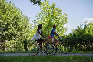 joven pareja multiétnica dando un paseo en bicicleta en la naturaleza foto