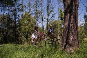 joven pareja multiétnica dando un paseo en bicicleta en la naturaleza foto