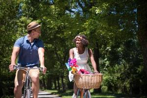 joven pareja multiétnica dando un paseo en bicicleta en la naturaleza foto