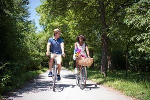 joven pareja multiétnica dando un paseo en bicicleta en la naturaleza foto