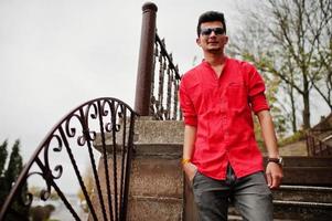 hombre indio con camisa roja y gafas de sol posó al aire libre. foto