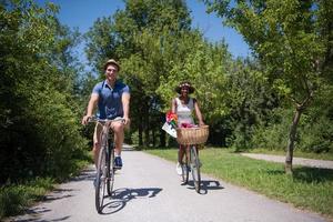 joven pareja multiétnica dando un paseo en bicicleta en la naturaleza foto