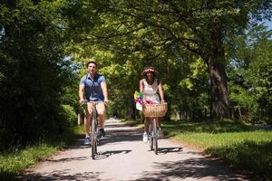 joven pareja multiétnica dando un paseo en bicicleta en la naturaleza foto