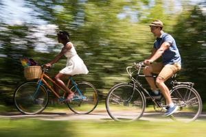 joven pareja multiétnica dando un paseo en bicicleta en la naturaleza foto