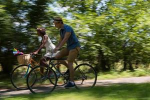 joven pareja multiétnica dando un paseo en bicicleta en la naturaleza foto