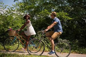 joven pareja multiétnica dando un paseo en bicicleta en la naturaleza foto