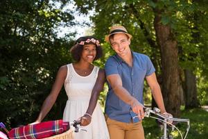 joven pareja multiétnica dando un paseo en bicicleta en la naturaleza foto