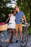 joven pareja multiétnica dando un paseo en bicicleta en la naturaleza foto