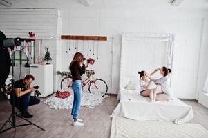 The team of two photographers shooting on studio twins girls while they make their own masks cream . Professional photographer on work. photo