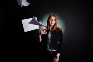 retrato de una mujer de negocios pelirroja con blusa a rayas y chaqueta tirando el papel. foto