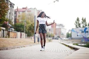 African american dark skinned slim model posed in a black leather shorts and white t-shirt. photo