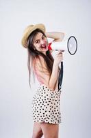 Portrait of a gorgeous young girl in swimming suit and hat talks into megaphone in studio. photo