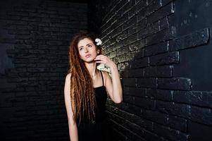 Studio shoot of girl in black with dreads on brick background. photo
