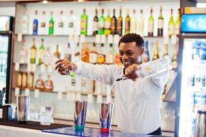 camarero afroamericano trabajando detrás del bar de cócteles. preparación de bebidas alcohólicas. foto