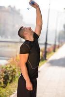 man pouring water from bottle on his head photo