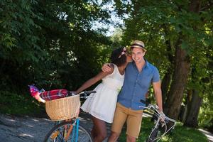 joven pareja multiétnica dando un paseo en bicicleta en la naturaleza foto