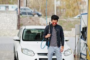 hombre del sur de asia o hombre indio lavando su transporte blanco en el lavado de autos. foto