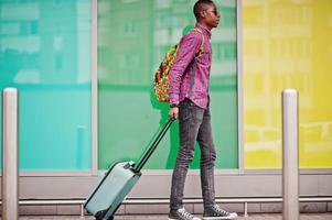 African american man in checkered shirt, sunglasses and jeans with suitcase. Black man traveler. photo