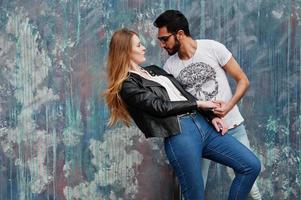 Cool multiracial couple posing against wall and dancing. photo